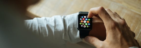 A closeup of someone tapping an Apple Watch icon they are wearing on their left wrist.